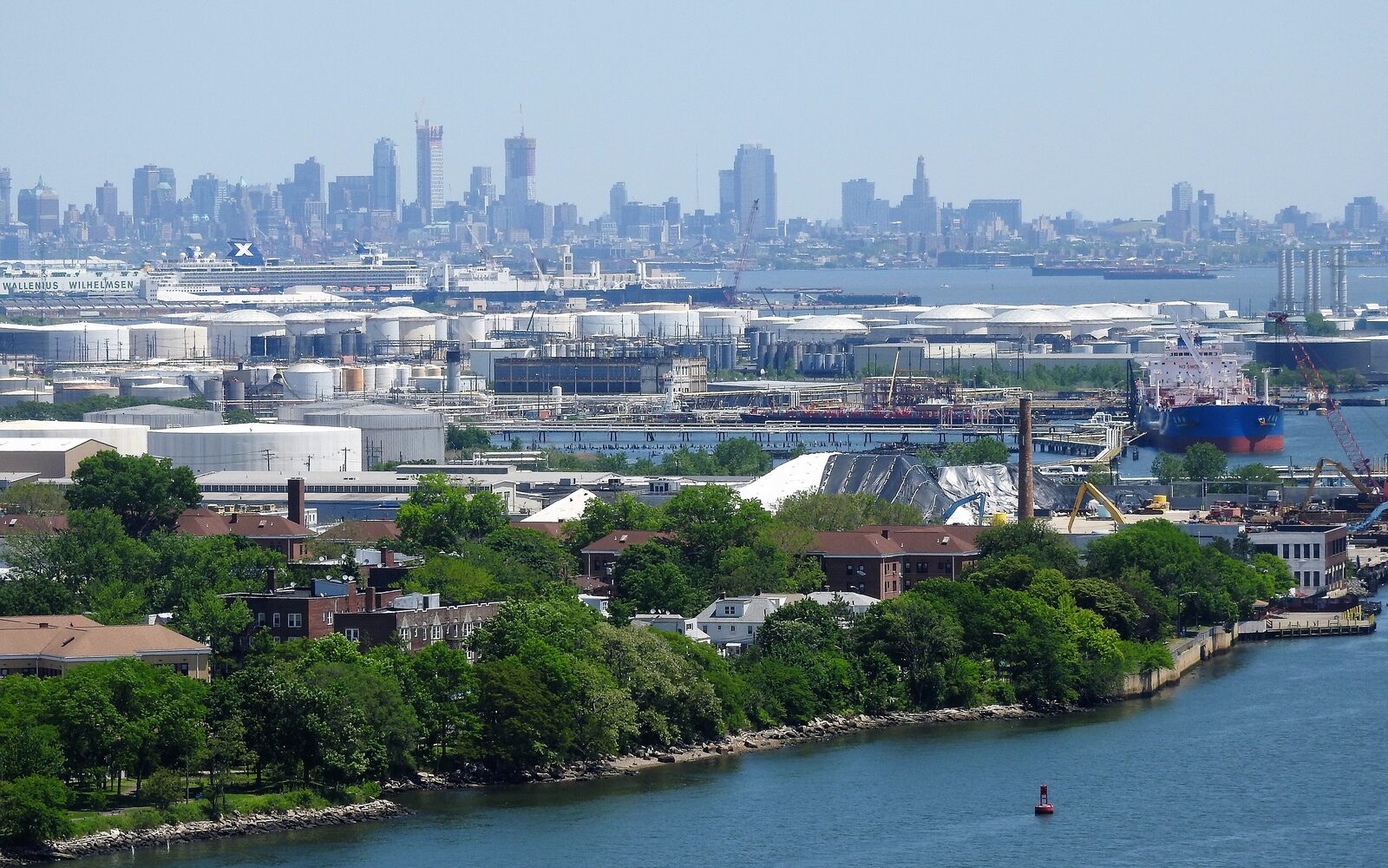 Elevated view over a dense cluster of storage tanks and terminal infrastructure beside a waterway
