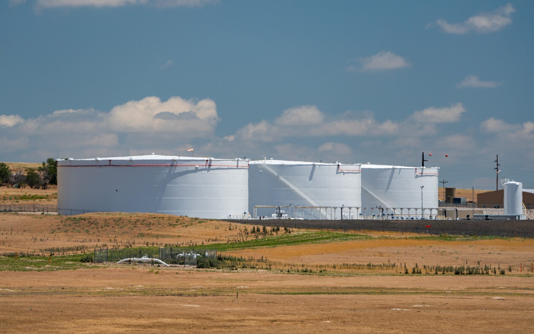 Extensive crude oil tank farm with numerous large cylindrical tanks joined by pipework