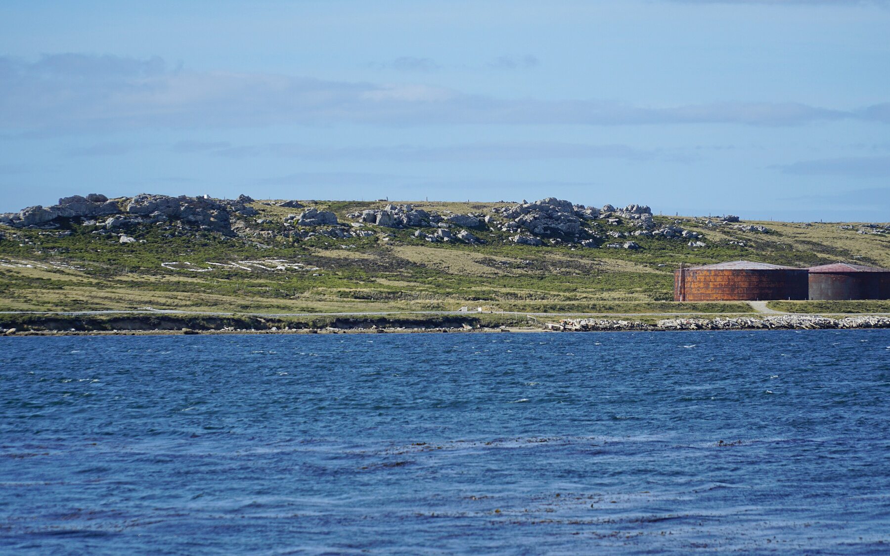 Coastal fuel depot with storage tanks and support buildings beside sheltered water